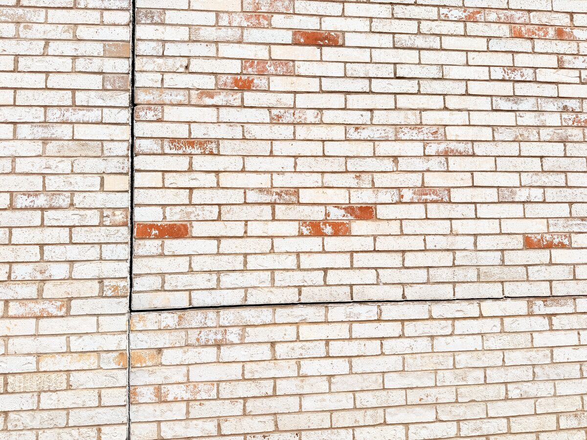 Horizontal and vertical repointed crack lines in painted brick following foundation stabilization