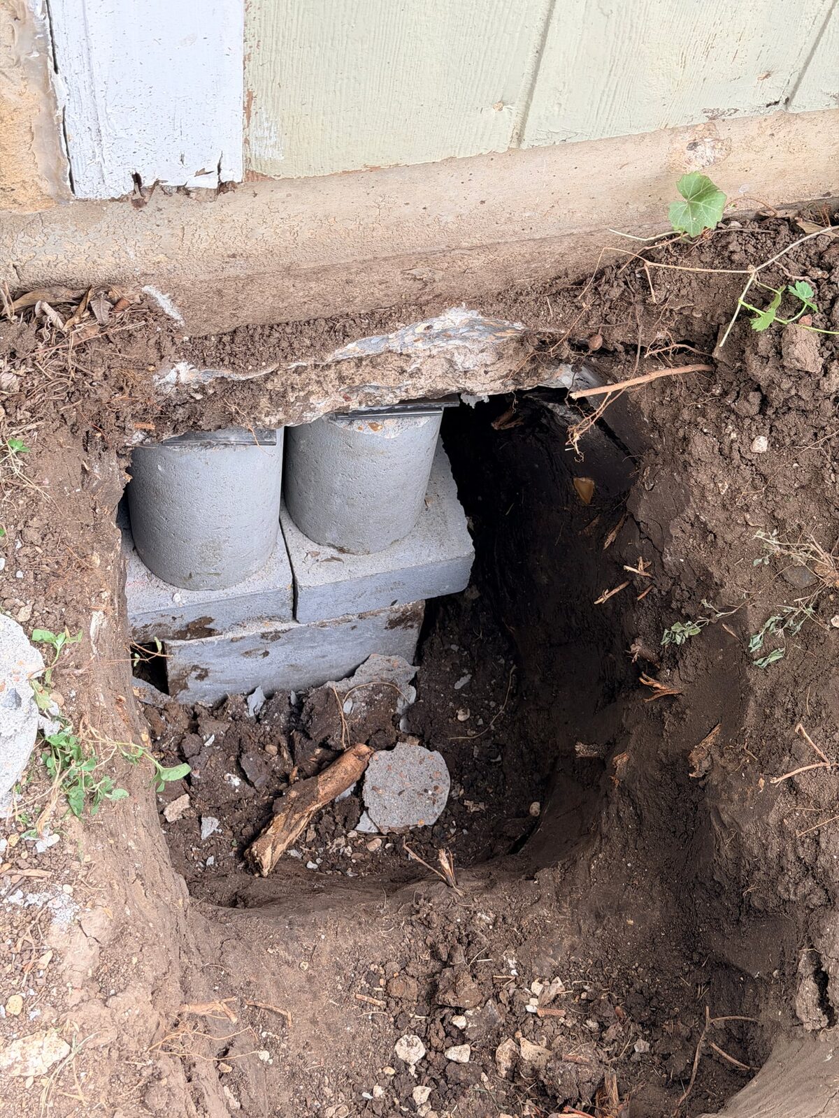 Top of a hybrid pier in a hand-dug hole, concrete cylinders on a cap block with steel shims set under the grade beam