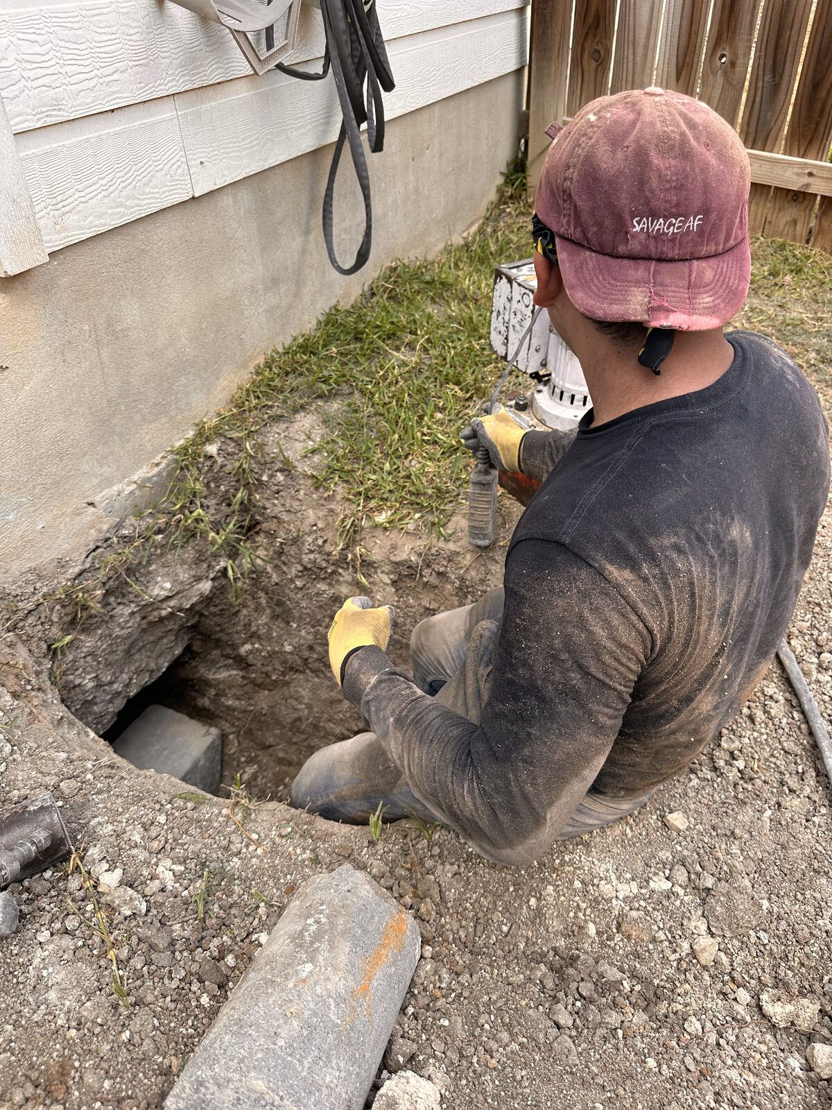 Crew operating a hydraulic ram pressing pilings beneath a foundation during a house leveling job