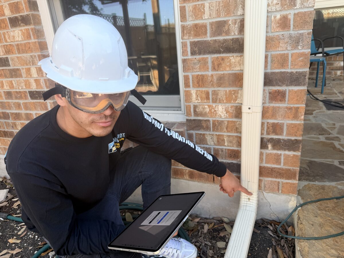 Motmot inspector documenting downspout and drainage notes on a tablet