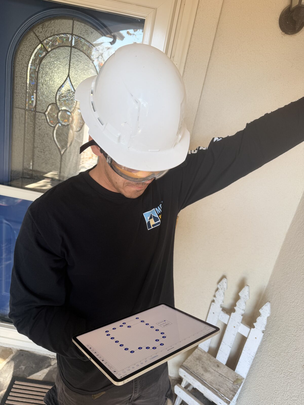 Inspector marking floor elevation readings on a tablet during a pier and beam inspection