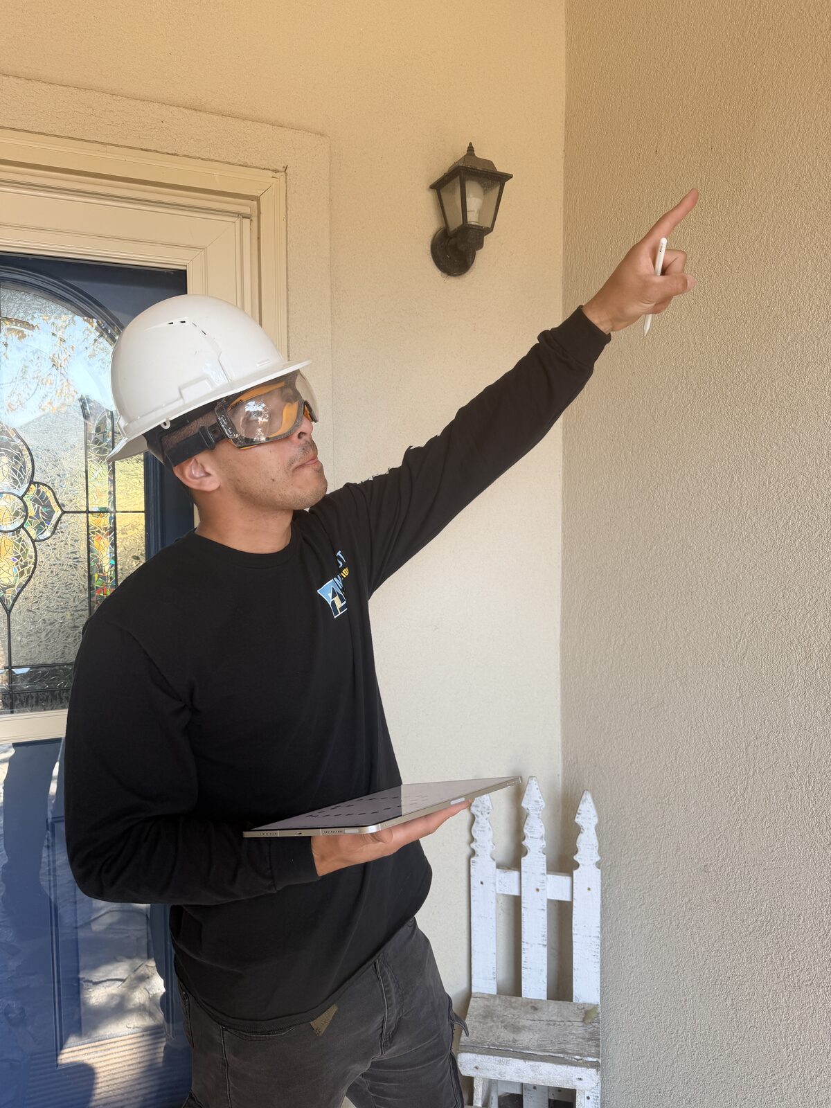 Inspector pointing at a porch ceiling while holding a survey tablet