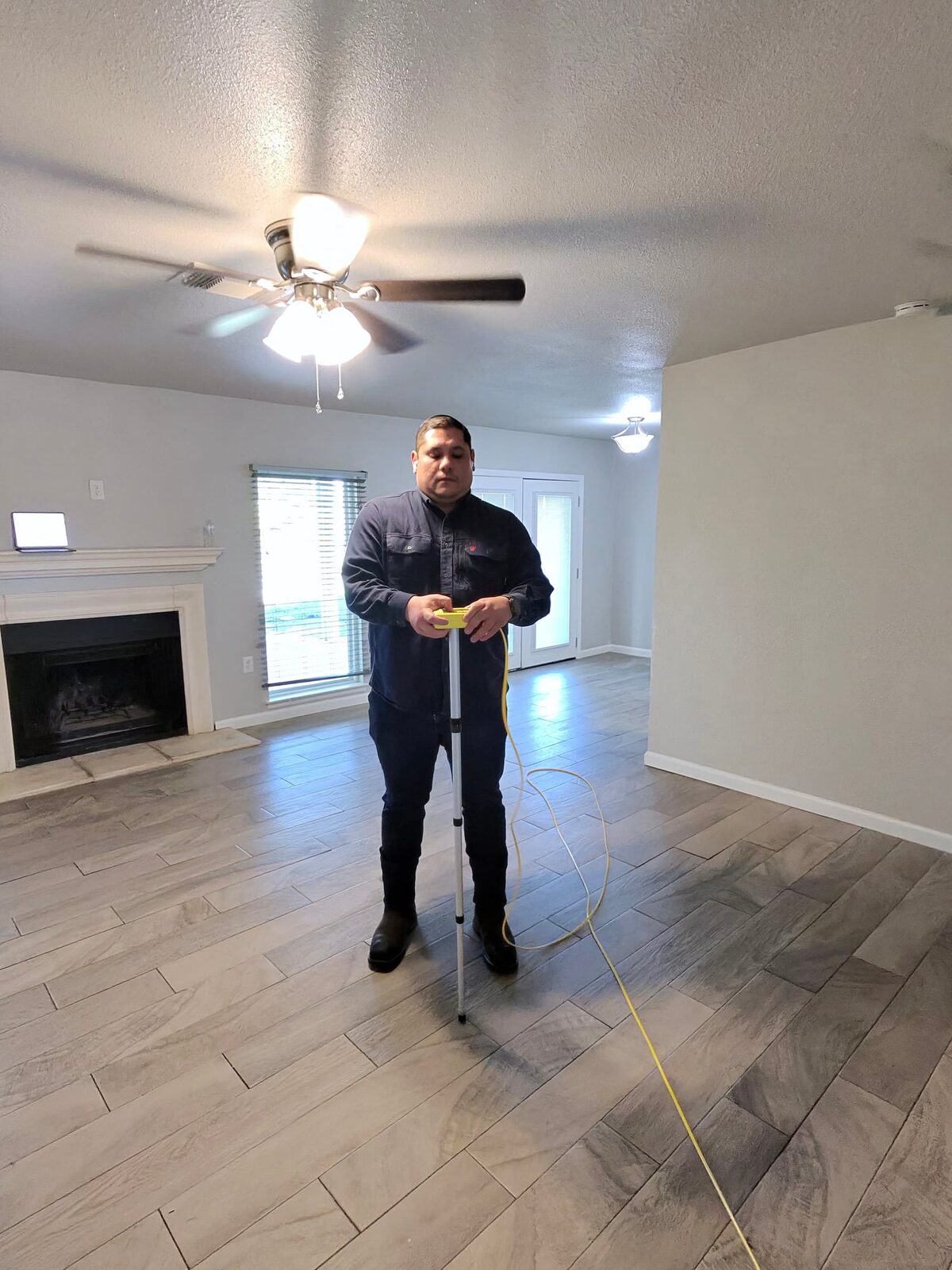 Inspector holding a ZipLevel sensor on a pole in the middle of a living room