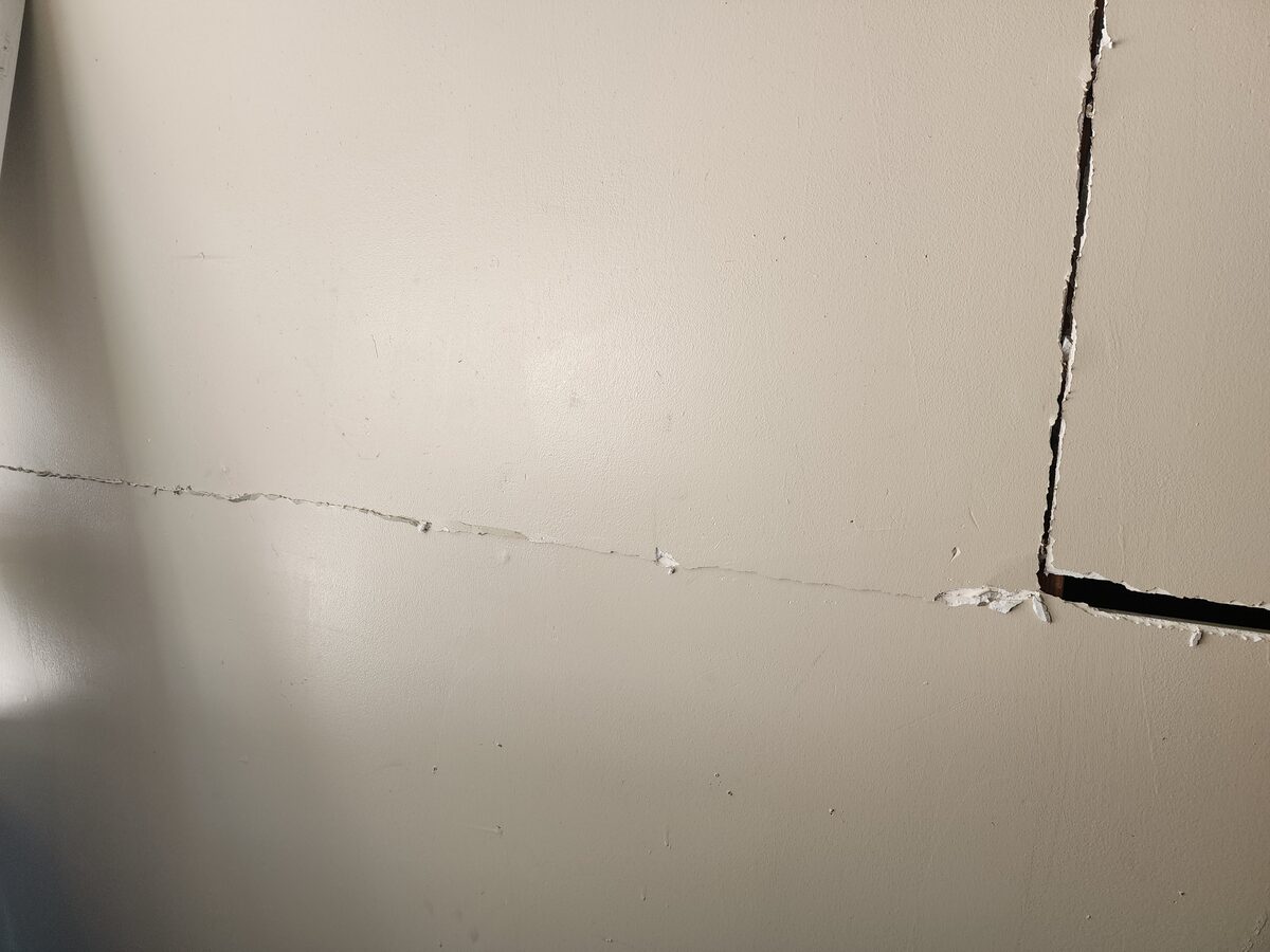 Close-up of intersecting horizontal and vertical drywall cracks caused by foundation movement