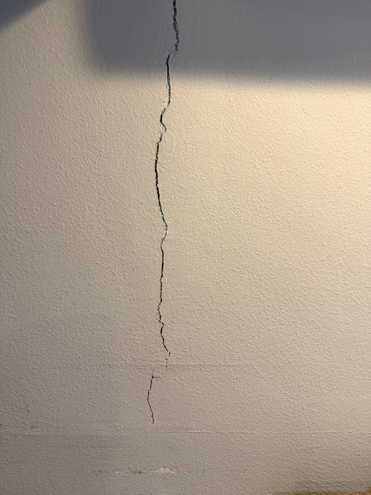 Jagged vertical crack running down an interior wall, a common symptom of foundation settlement