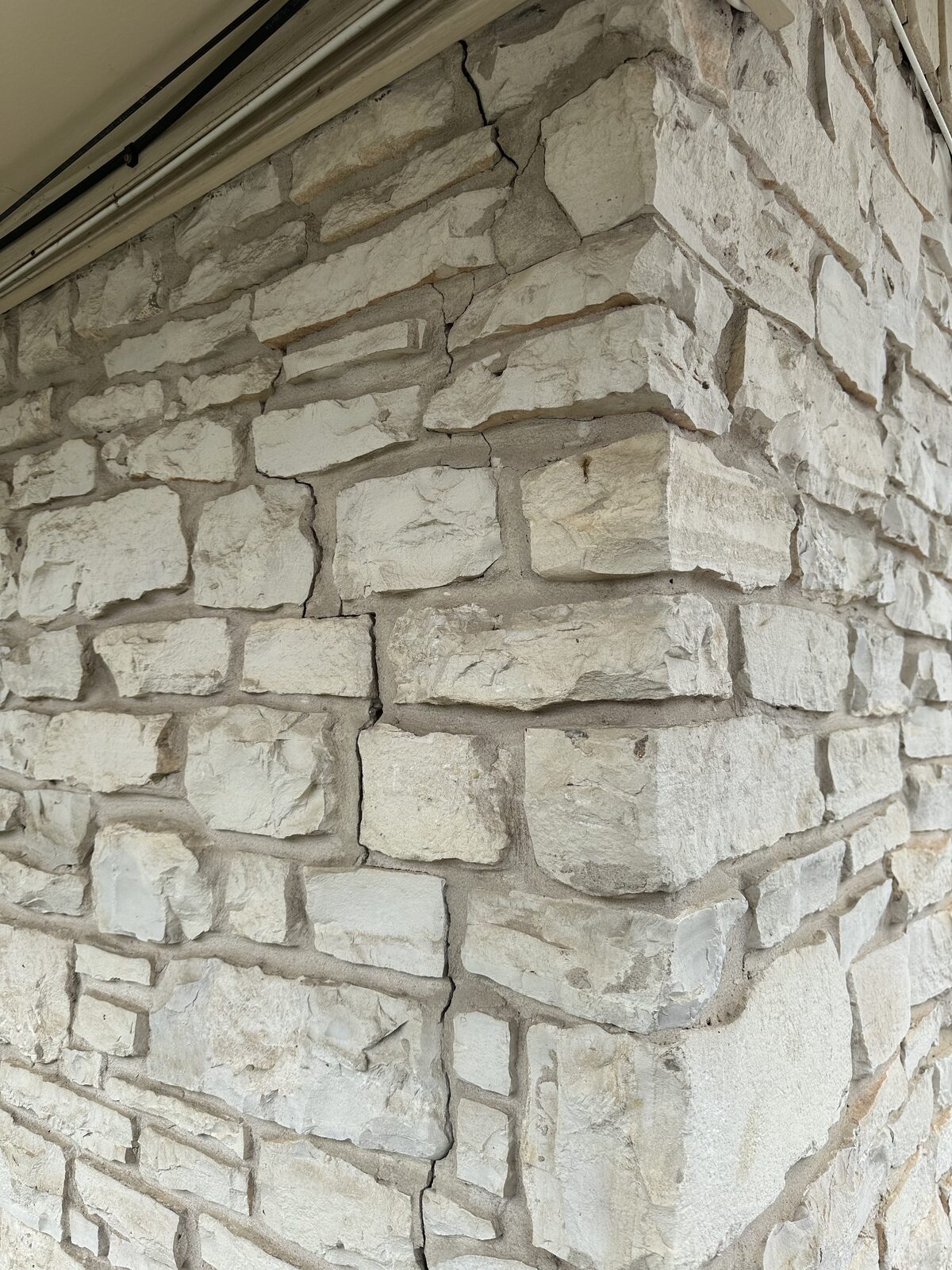 Vertical cracks at the corner of a white limestone veneer wall, documented before commercial foundation repair