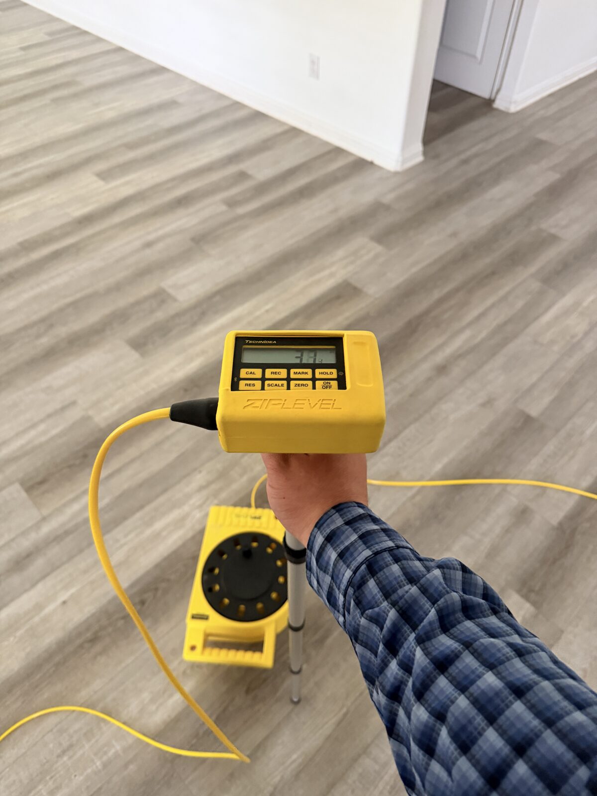 Inspector holding an elevation meter with base unit on the floor nearby
