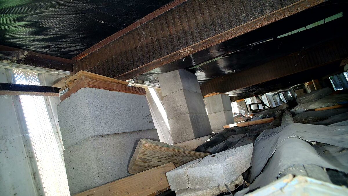 Steel frame rails resting on stacked concrete block piers under a manufactured home