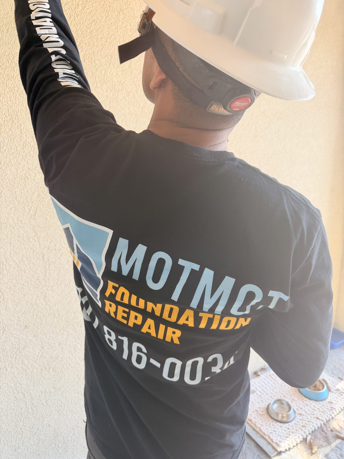 Motmot Foundation Repair technician in branded shirt pointing out damage during a home inspection