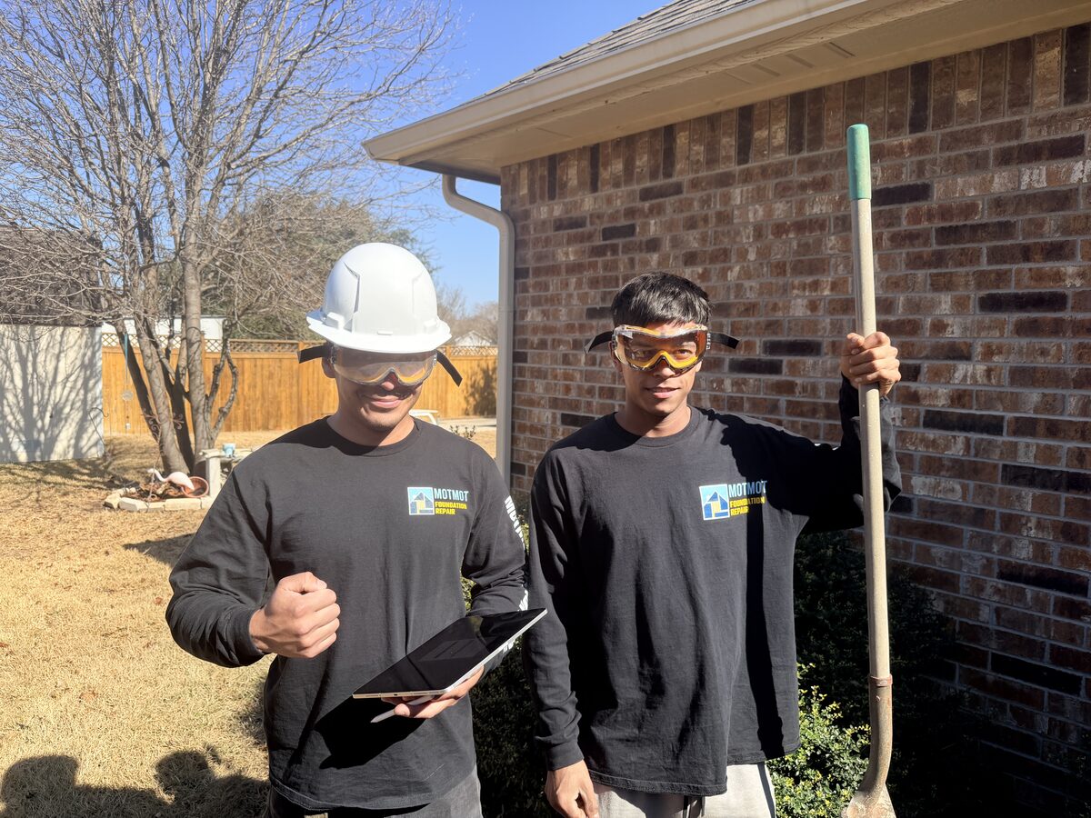 Motmot Foundation Repair crew members with shovel and tablet outside a brick home after an inspection
