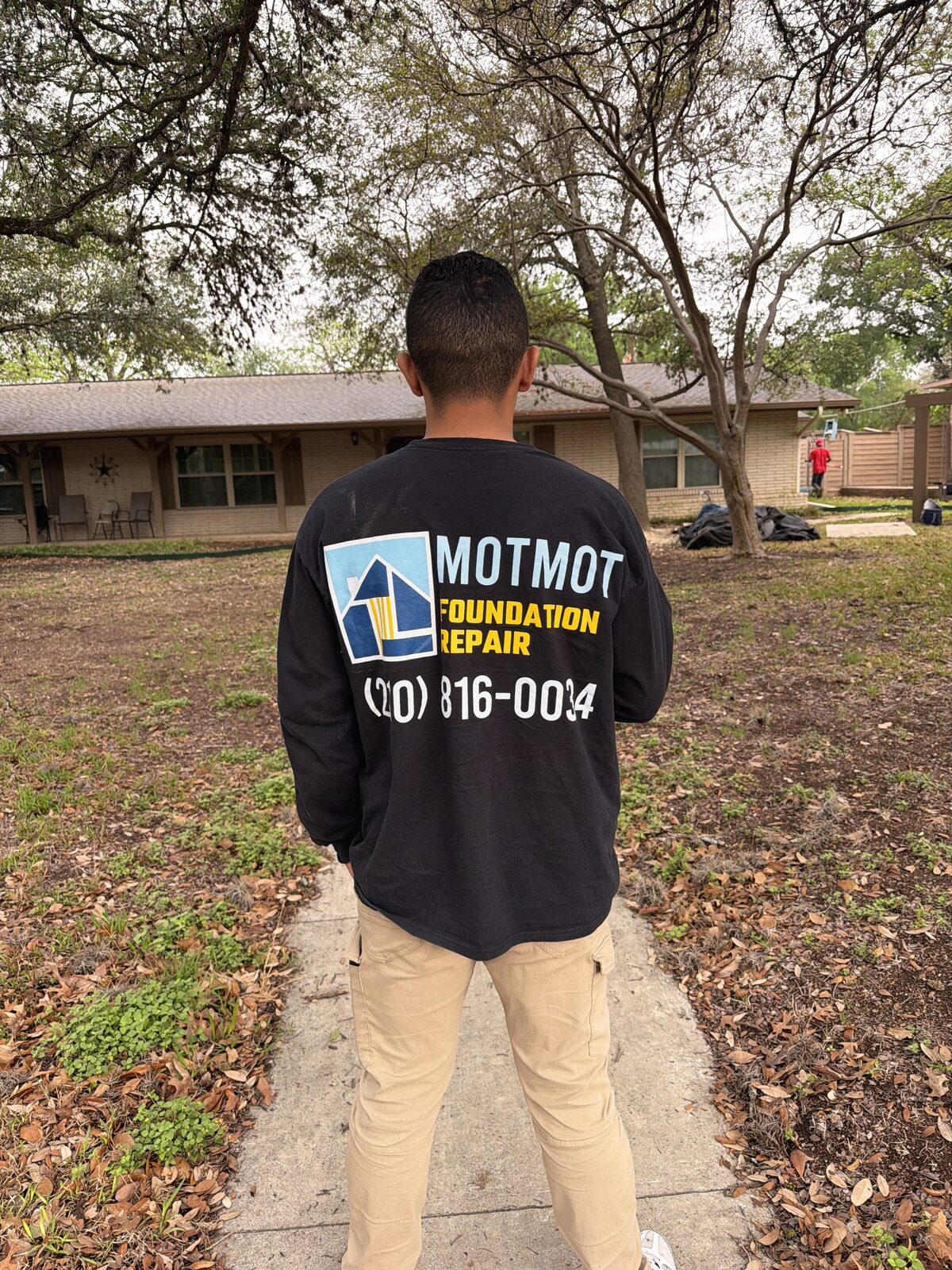 Motmot Foundation Repair technician in a branded company shirt at a residential job site
