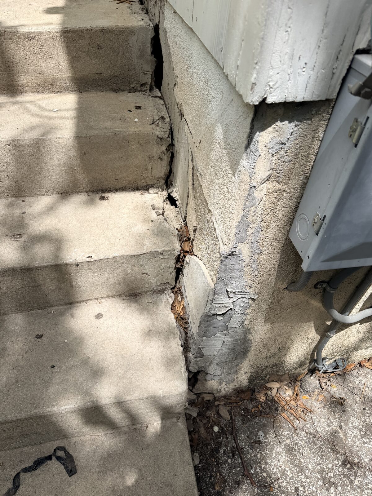 Cracked patch material reopening along a stucco perimeter beam at porch steps