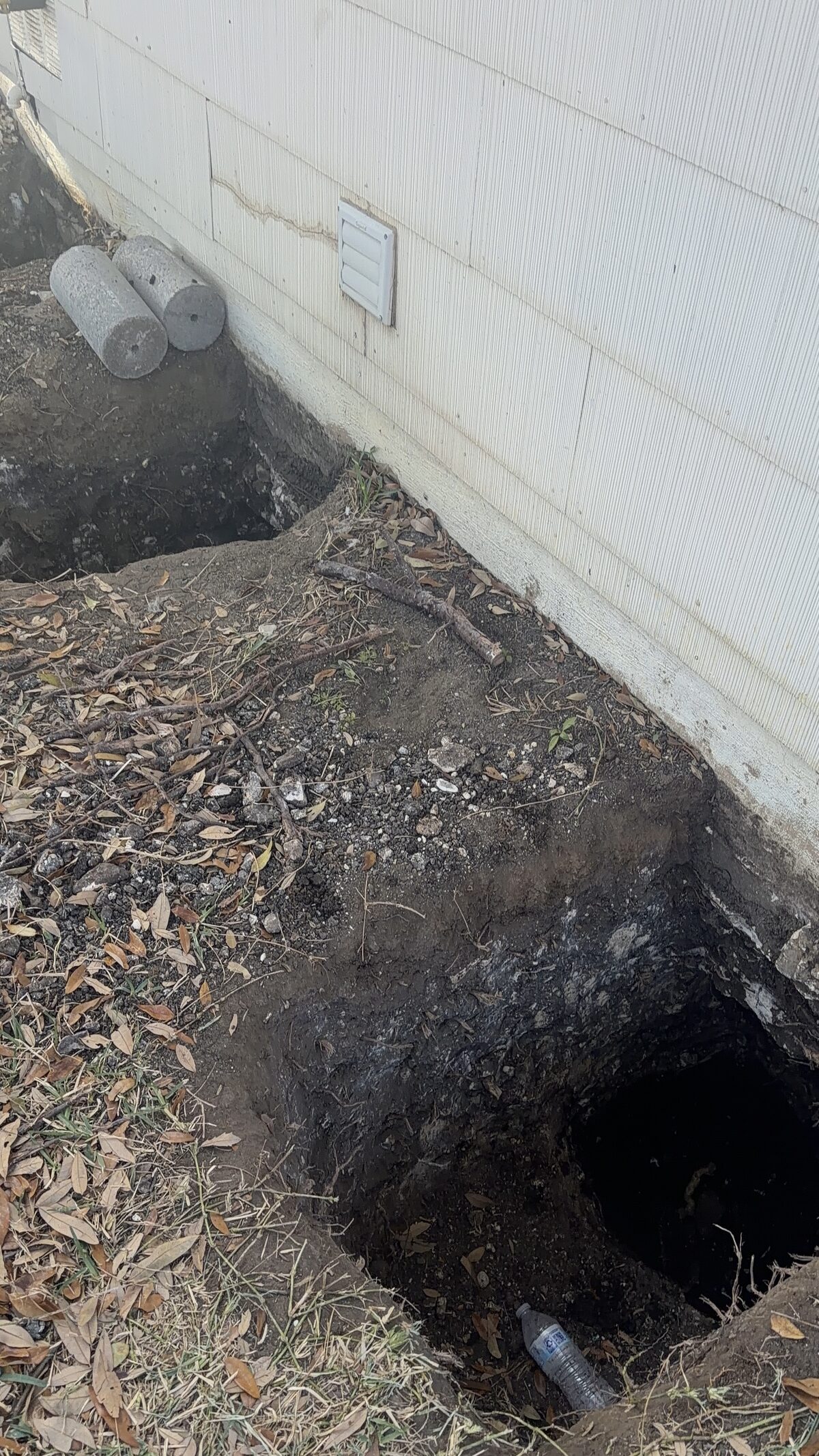 Pier hole excavated at the base of a wall to access the slab grade beam for repair