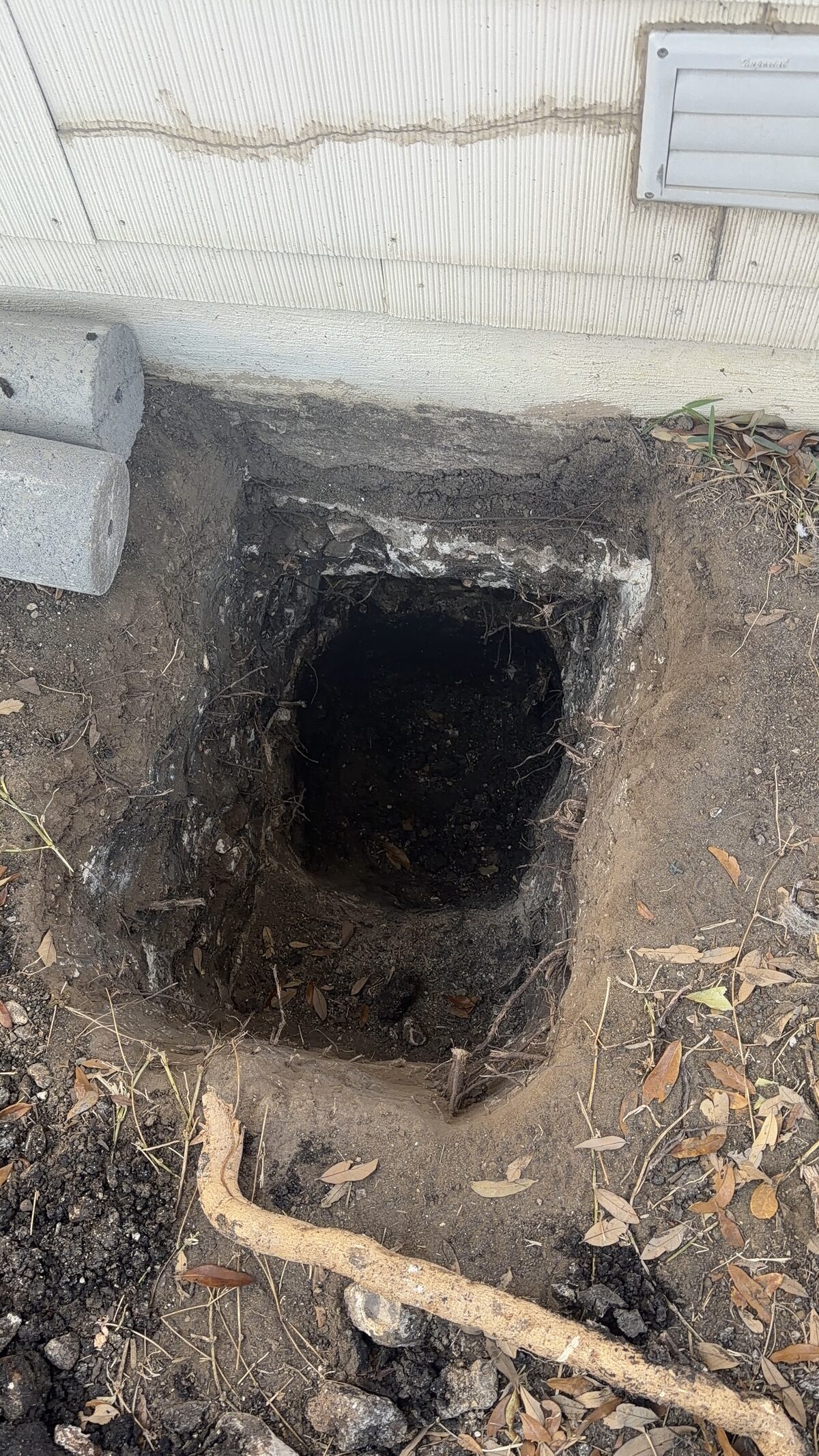 Pier hole dug to expose the existing concrete footing of a slab foundation