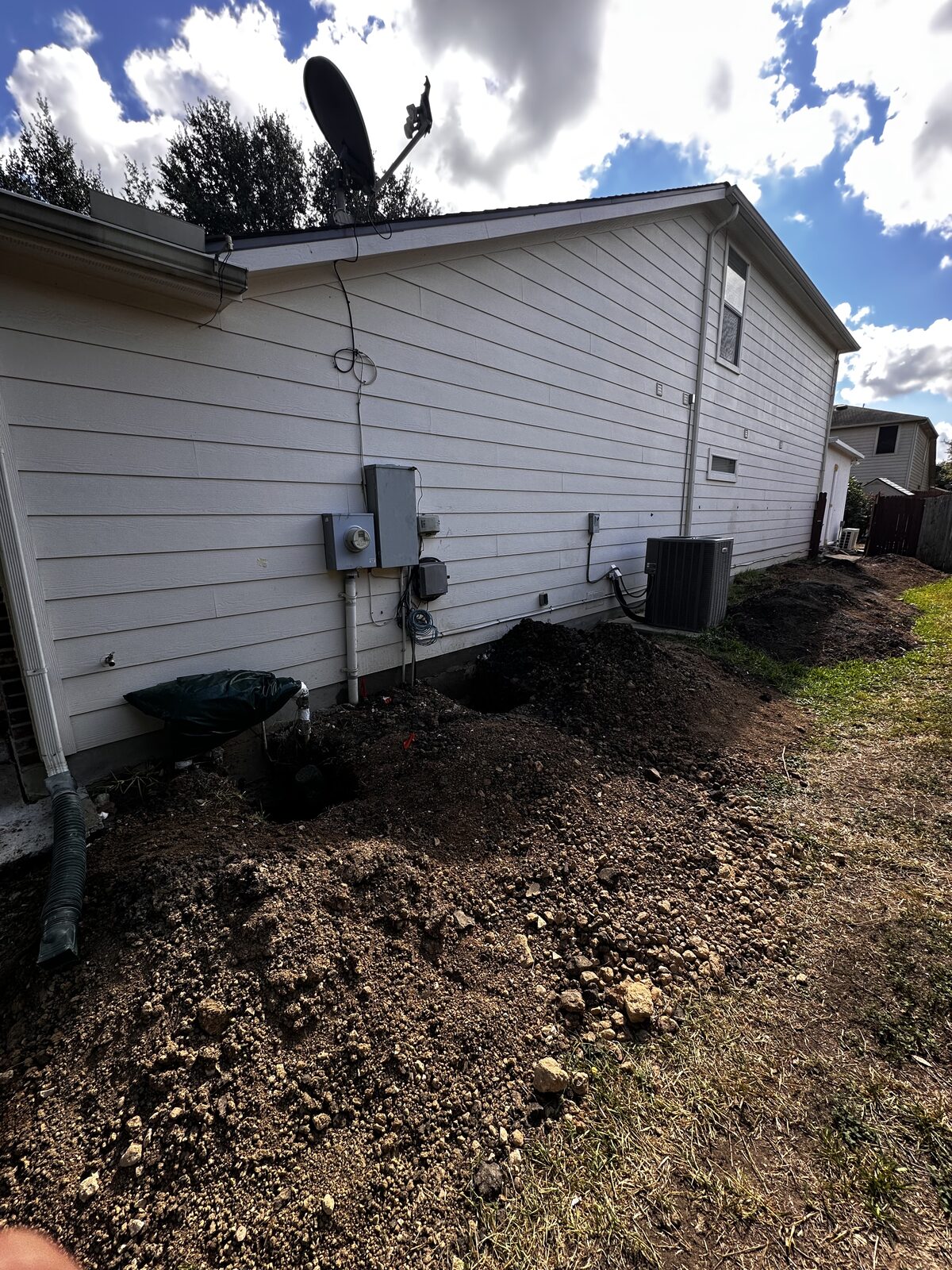 Series of pier holes dug along the exterior of a home ahead of foundation pier installation