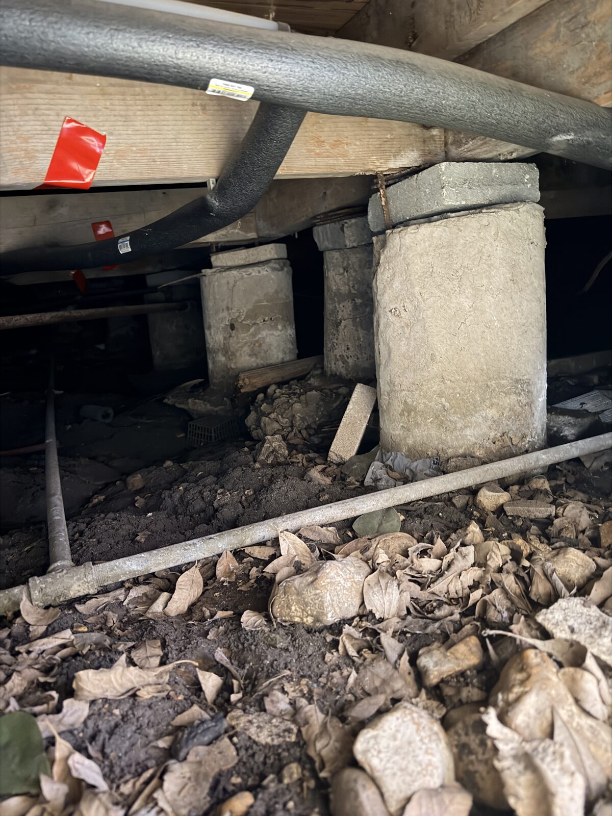 Concrete pier sections and block pieces packed under a house edge