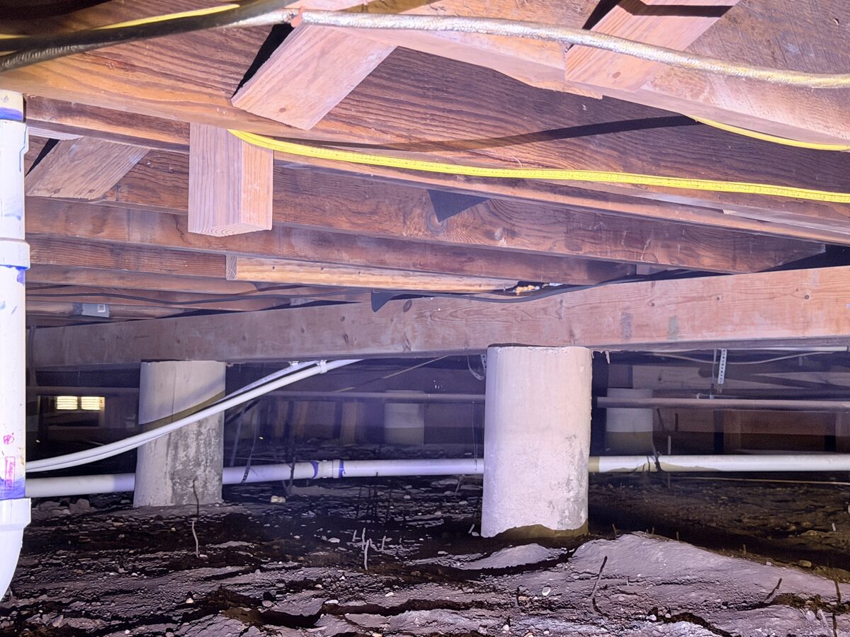 Concrete piers, beams, and joists beneath the floor of a pier and beam house