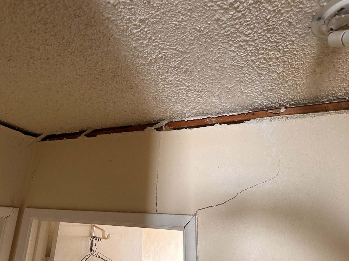 Plaster crack at the ceiling corner beside a door frame caused by foundation settlement