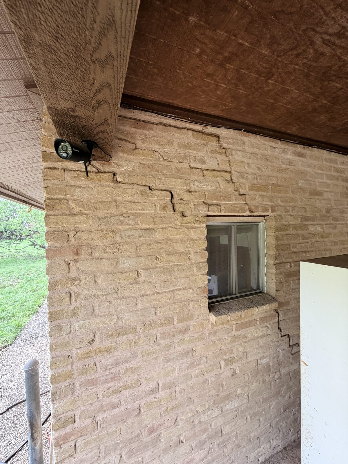 Branching cracks in the brick at a porch corner on a 1920s bungalow, from foundation settlement