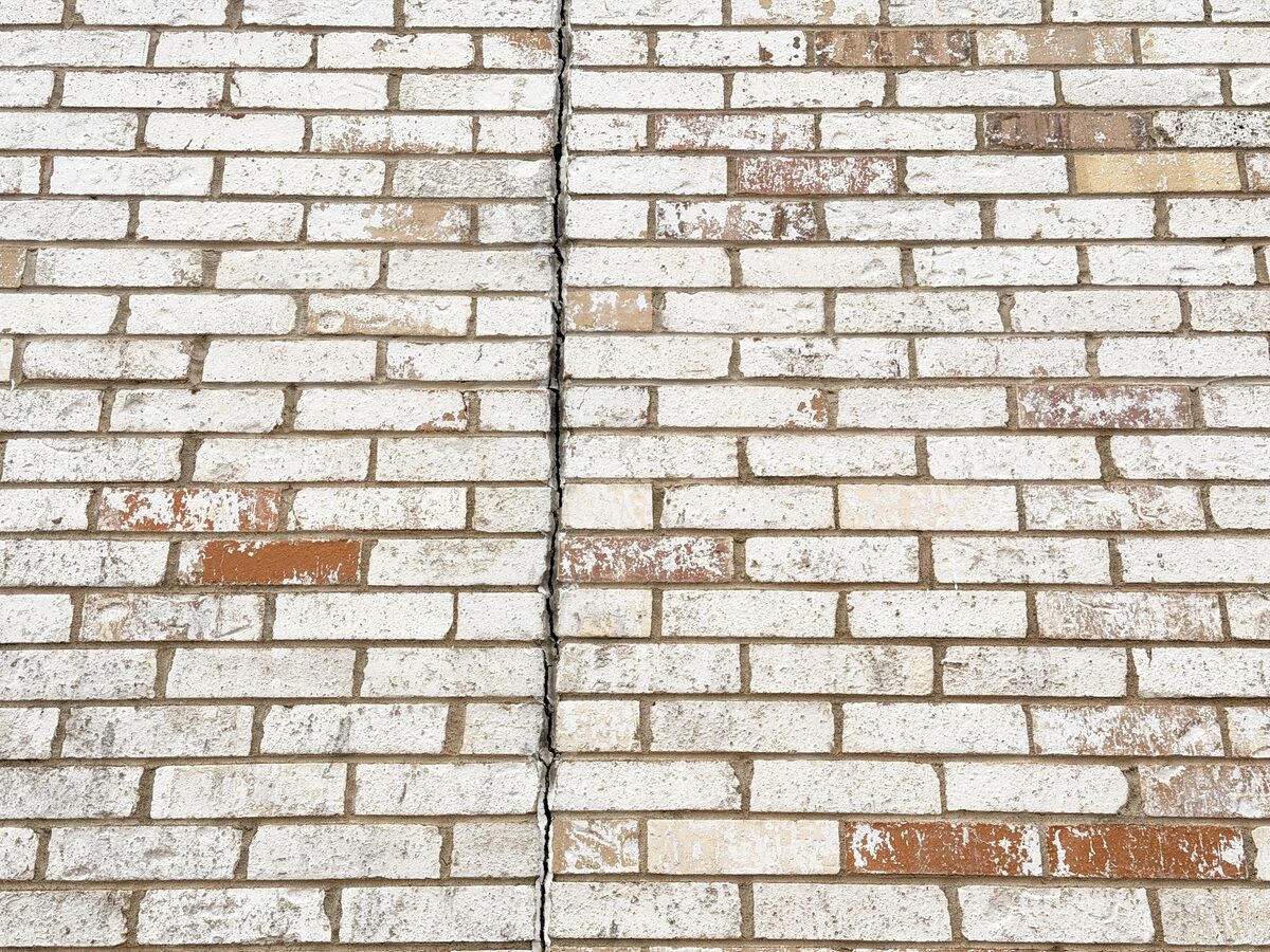 Straight-on view of a vertical mortar joint repointed in painted brick after foundation movement