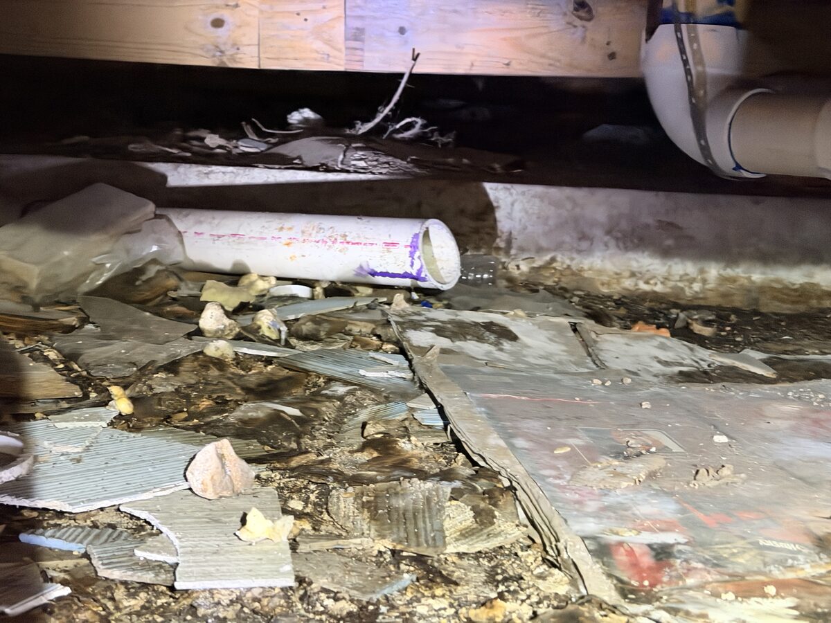 Rotted delaminating subfloor edges above a beam in a crawl space