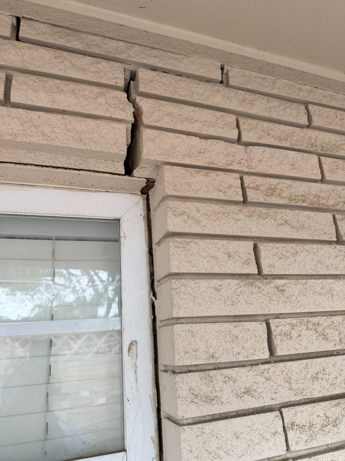 Stair-step crack in brick beside a window, a common Central Texas foundation symptom