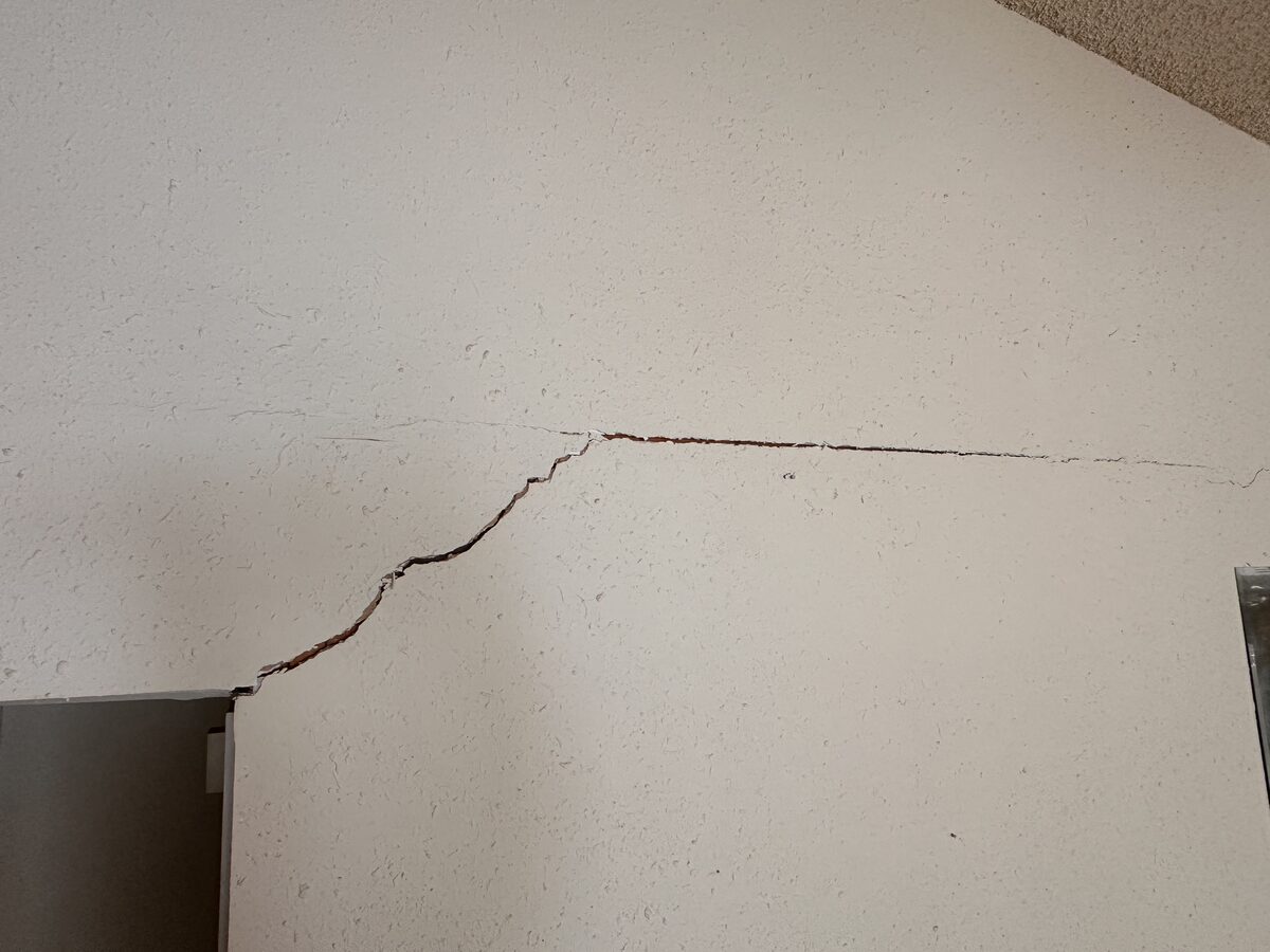 Stair-step crack spreading from a door frame across the wall, a classic sign of foundation settlement