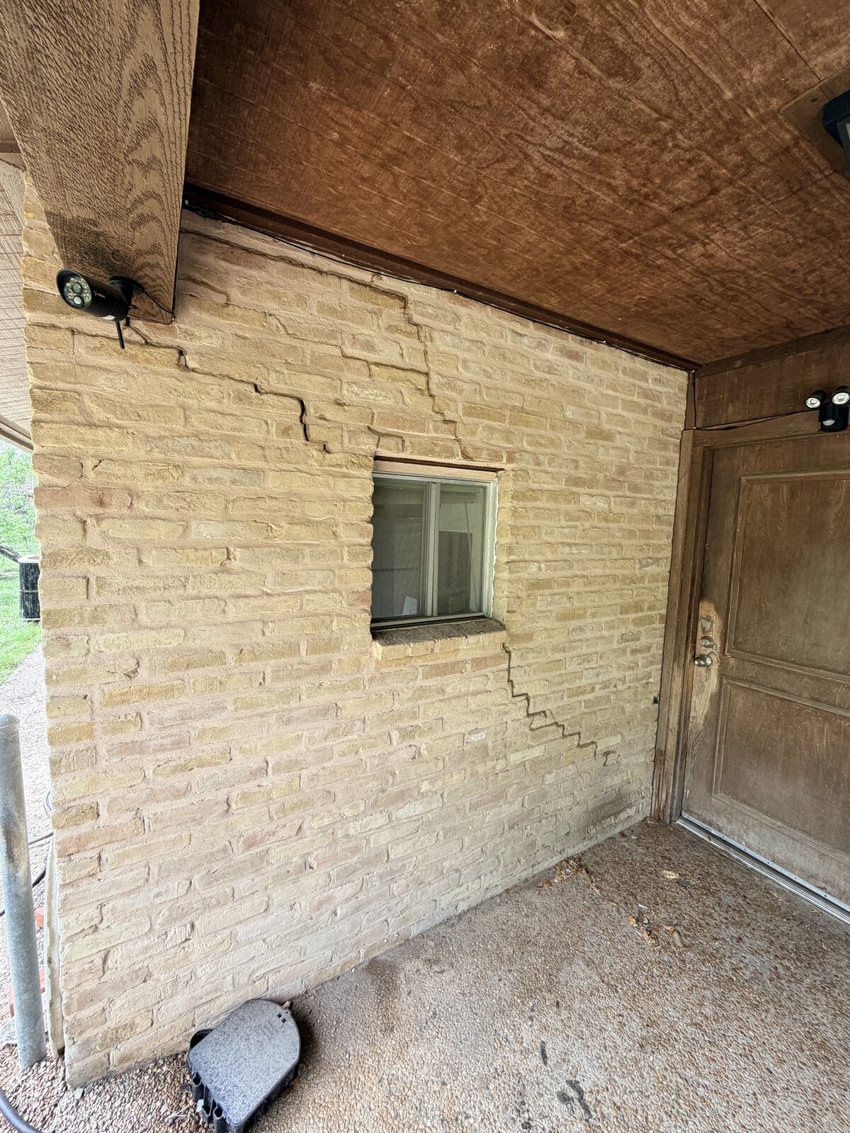 Stair-step brick crack between a porch window and door