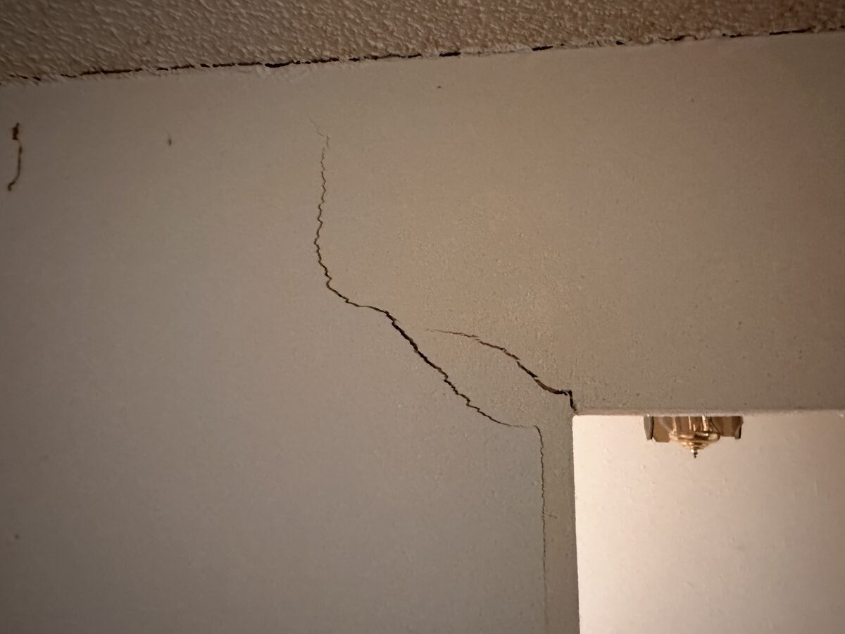 Large stair-step crack where a vaulted ceiling meets the wall above a hallway opening