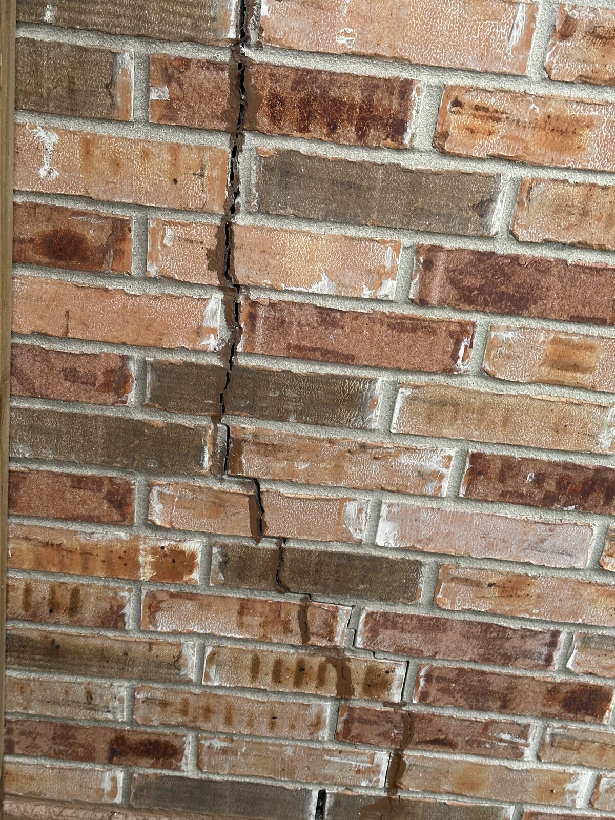 Close-up of stair-step cracking through brick mortar joints, a hallmark of foundation settlement