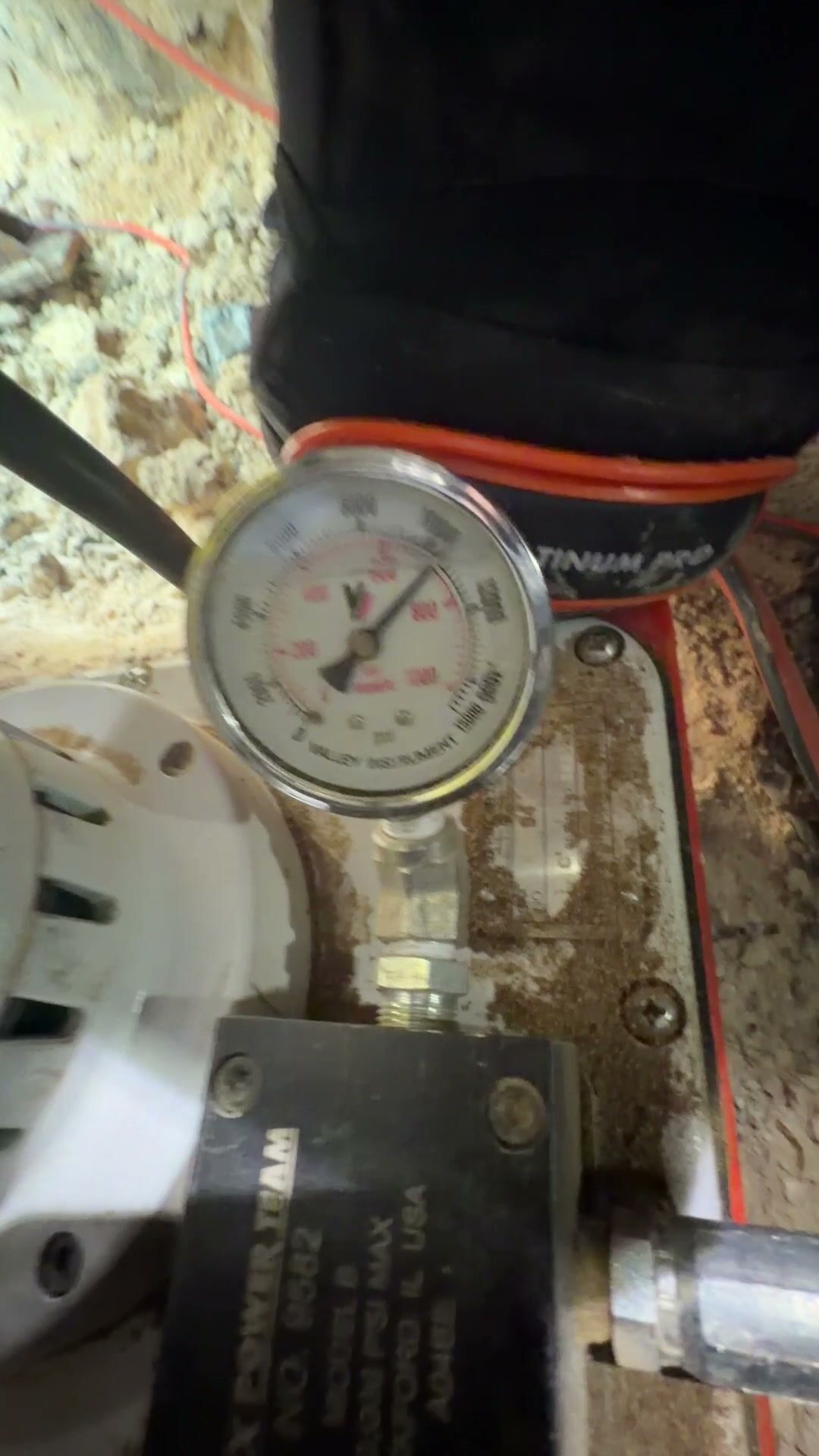 Pressure gauge on the hydraulic pump reading while a steel pier is driven under a slab