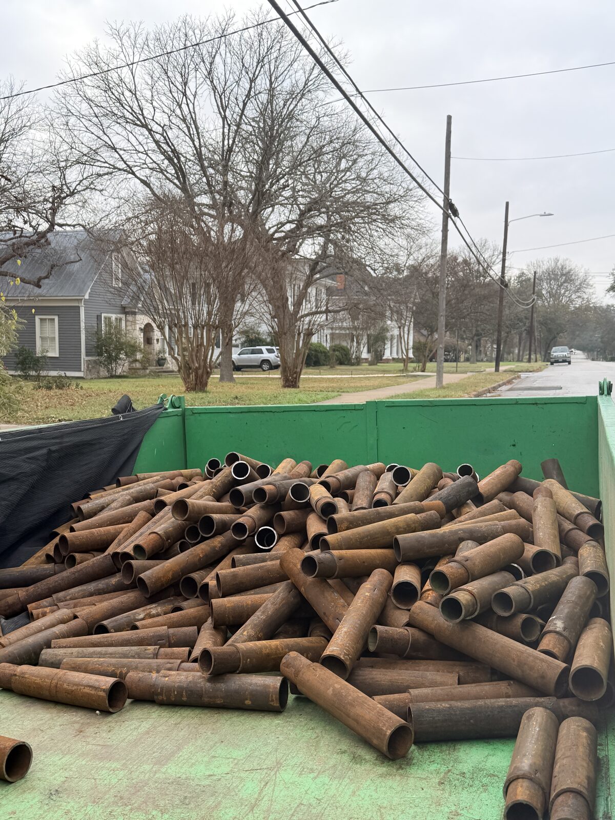 Trailer loaded with steel pier pipe sections staged for a foundation repair job in a San Antonio neighborhood