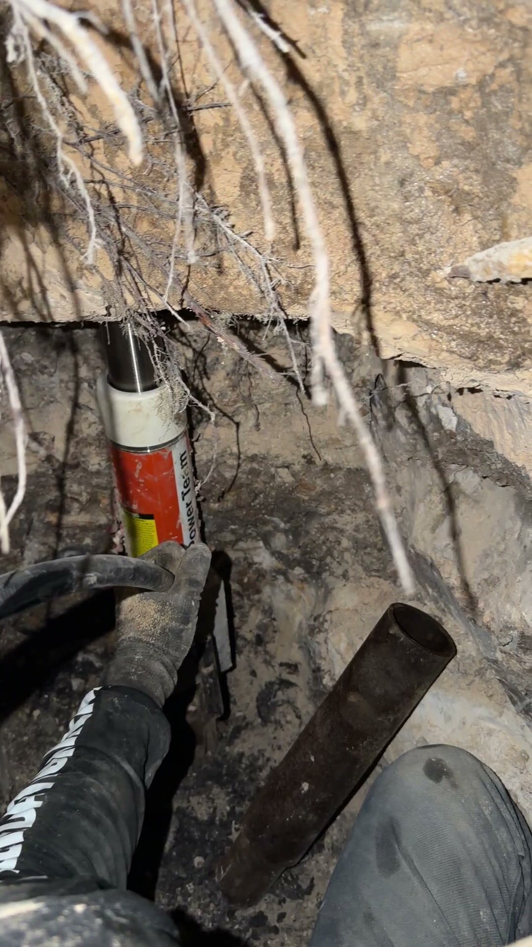 Crew member setting the next steel pipe section under the ram inside a tunnel below the slab
