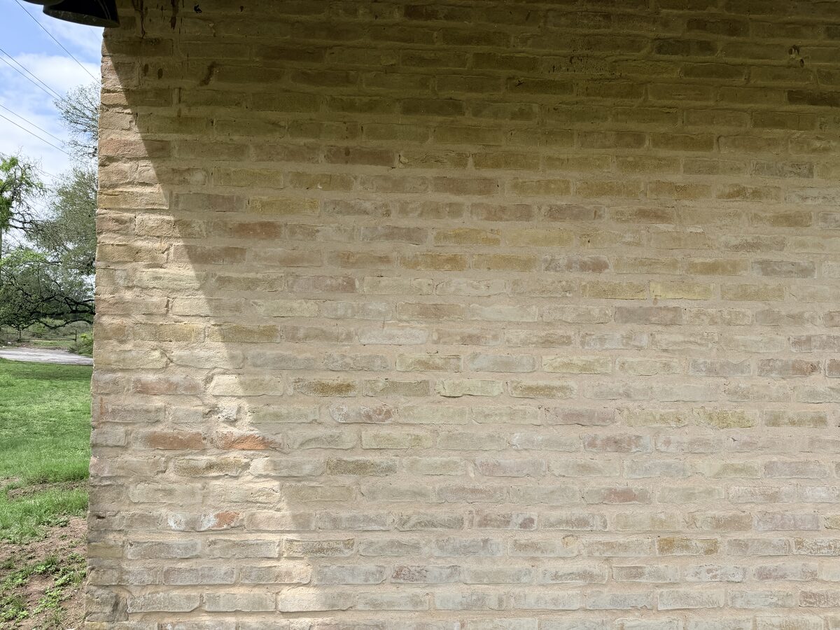 Tan brick wall corner being surveyed during a foundation inspection