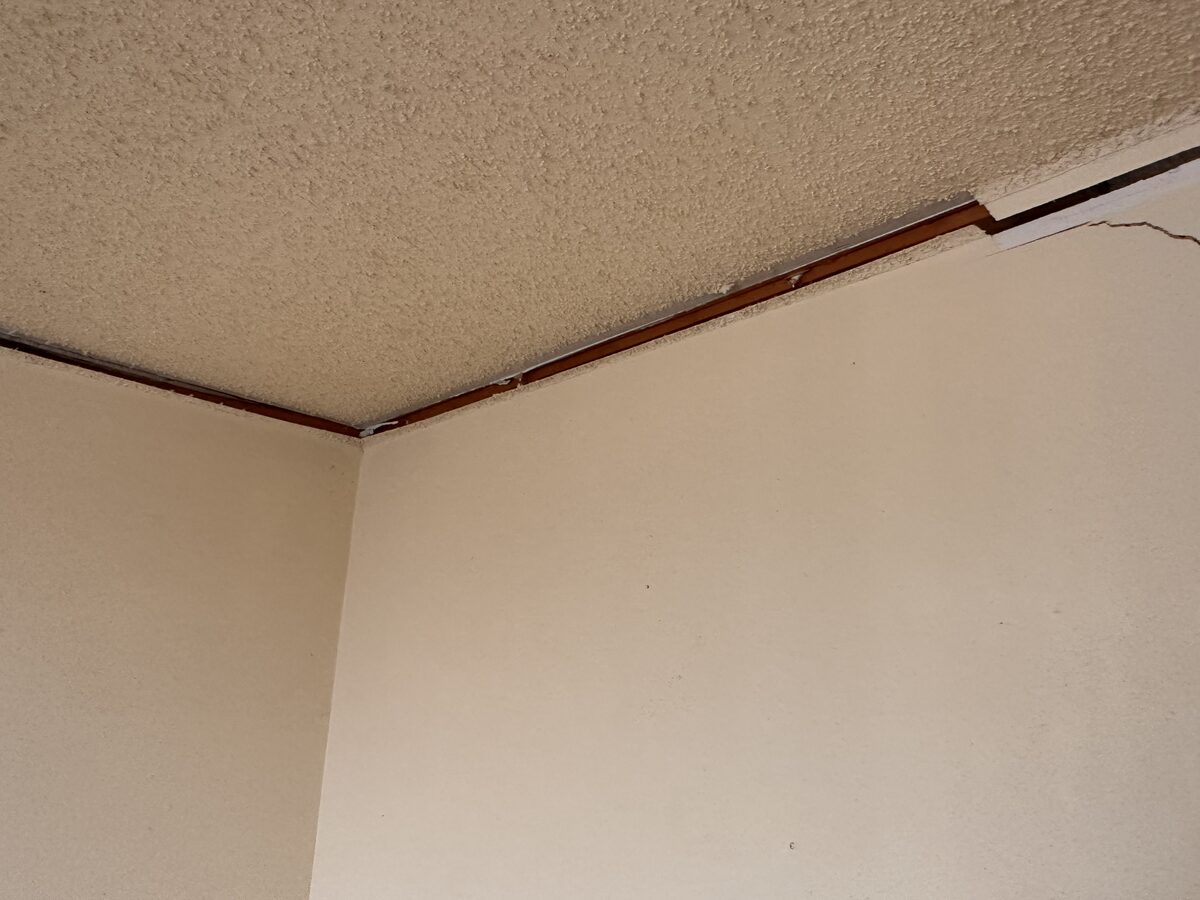 Trim pulling away from a textured ceiling at a wall corner in a home with settlement issues