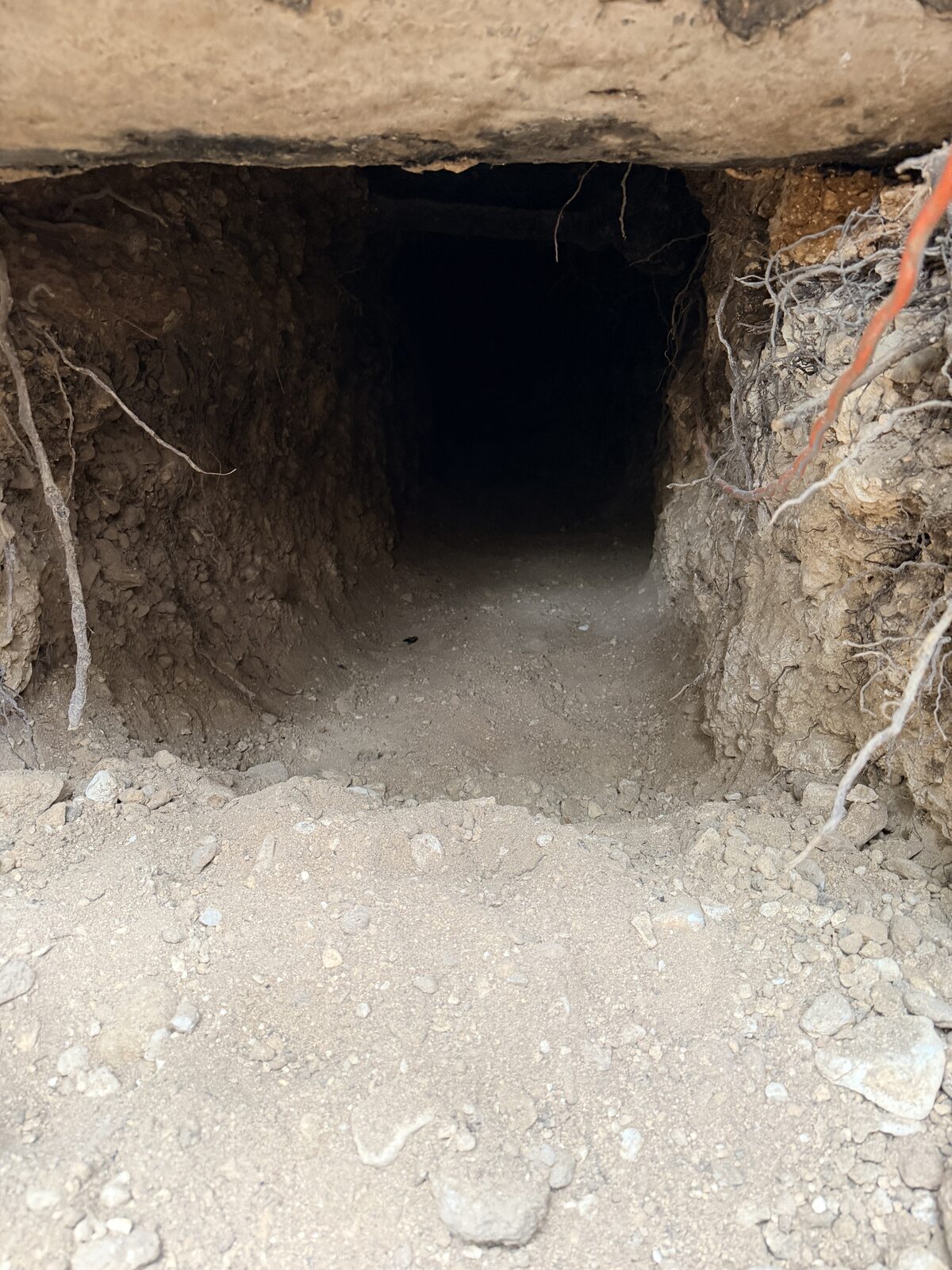 Access tunnel hand-dug beneath a concrete slab foundation to install support piers under the home
