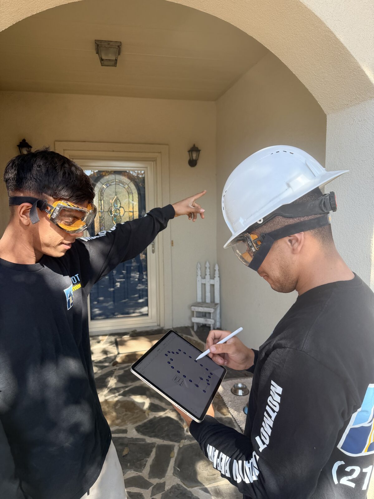 Two Motmot crew members taking inspection notes on a tablet at a home's porch