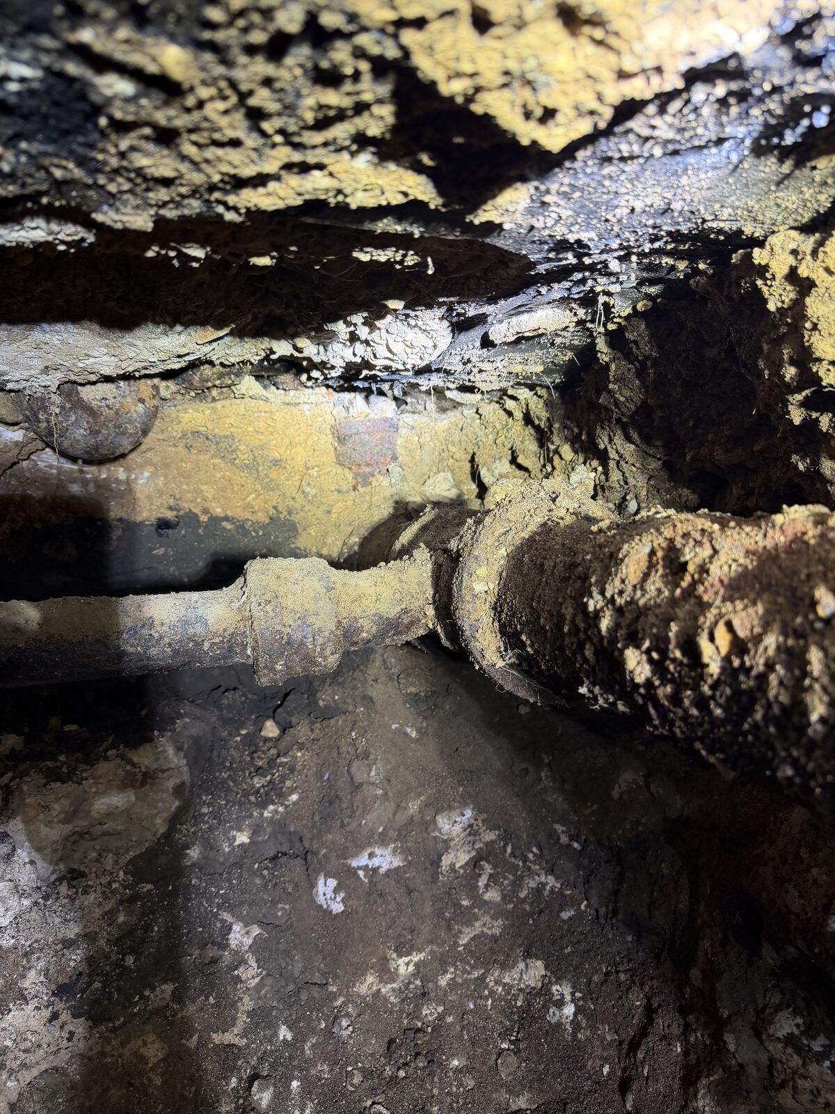 A failed under-slab line exposed in a tunnel — the source reached so the plumber can stop it.