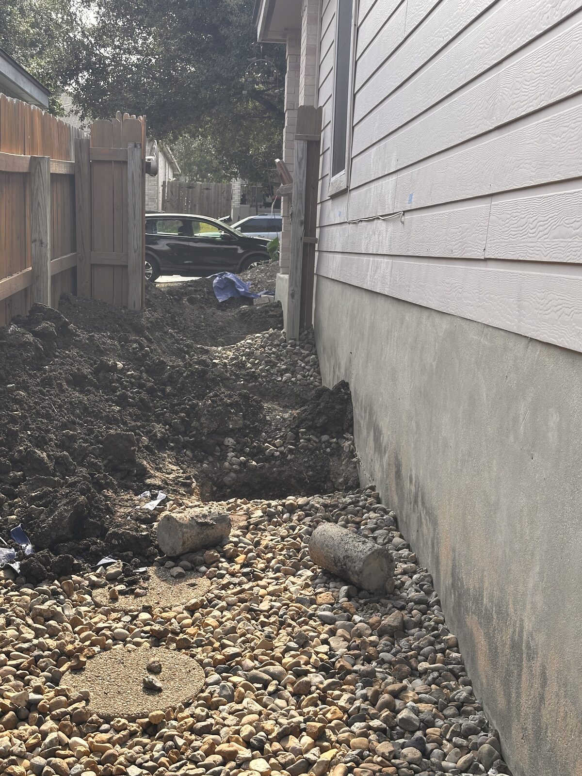 Footing undermined for pier placement beneath a stem wall in a river-rock side yard
