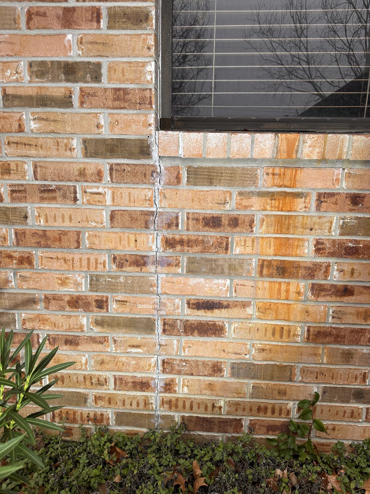 Vertical crack in brick veneer running from a window sill down to grade, flagged during a foundation inspection