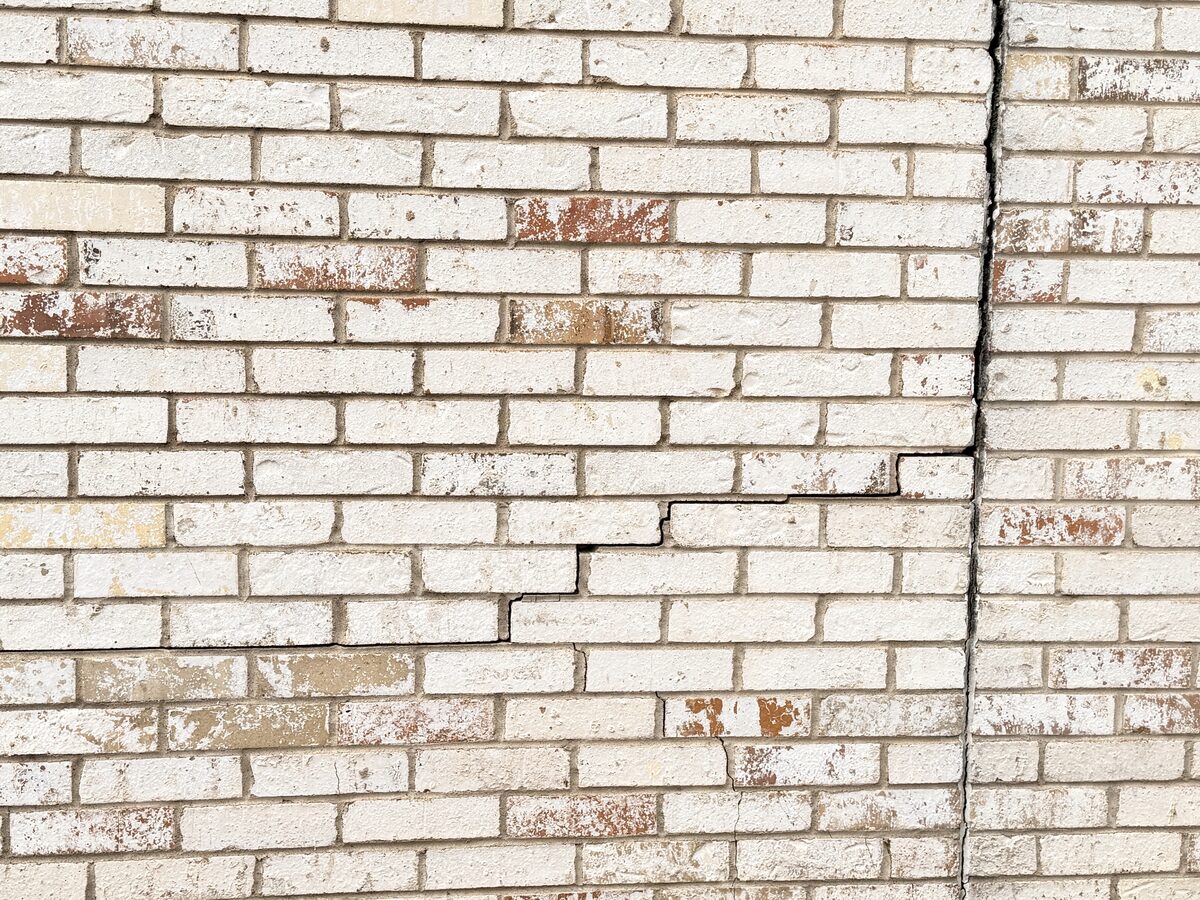 Vertical crack line along a white brick wall, documented during a foundation repair project