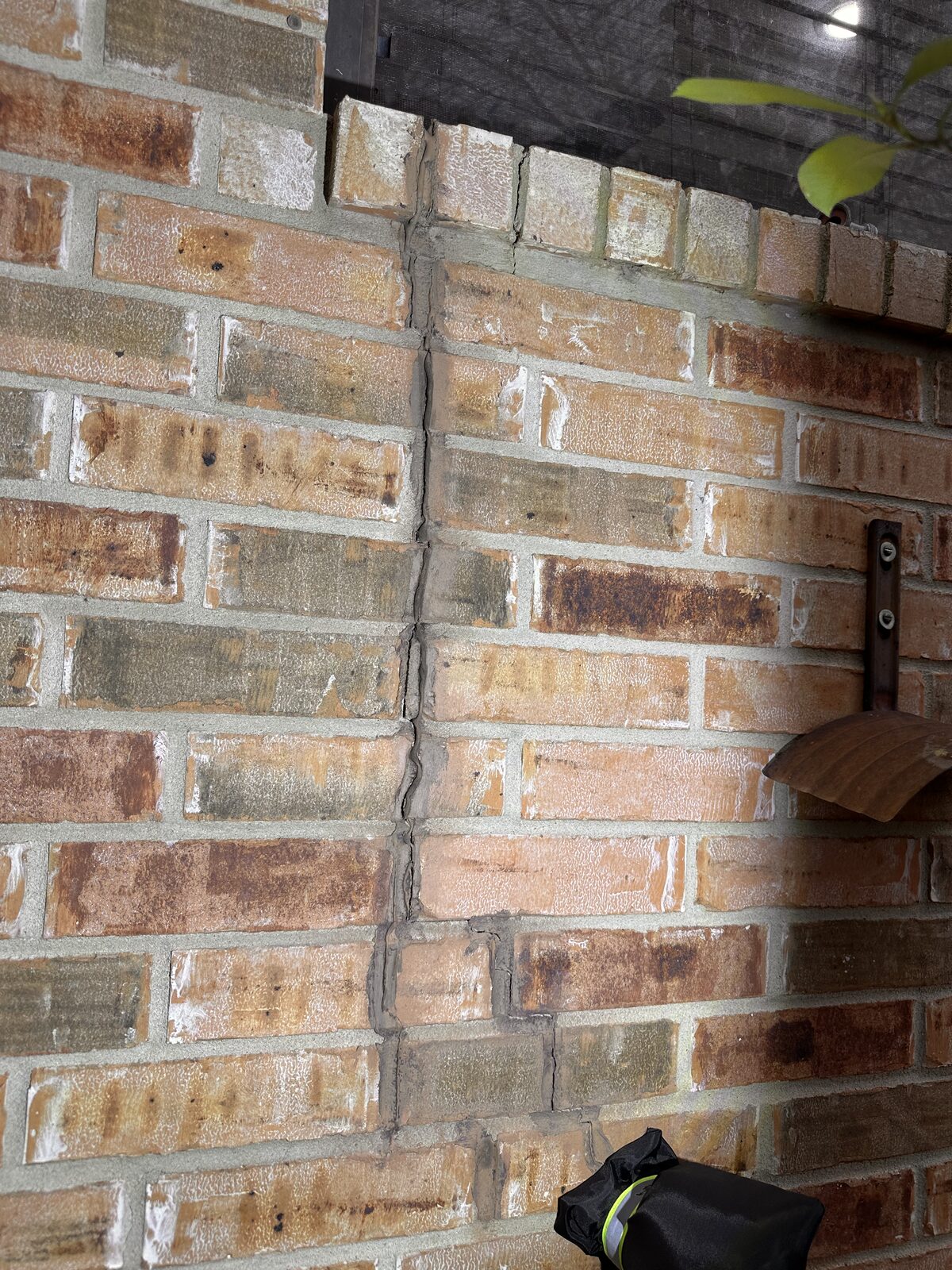 Long vertical crack splitting brick veneer below a porch corner, caused by foundation movement