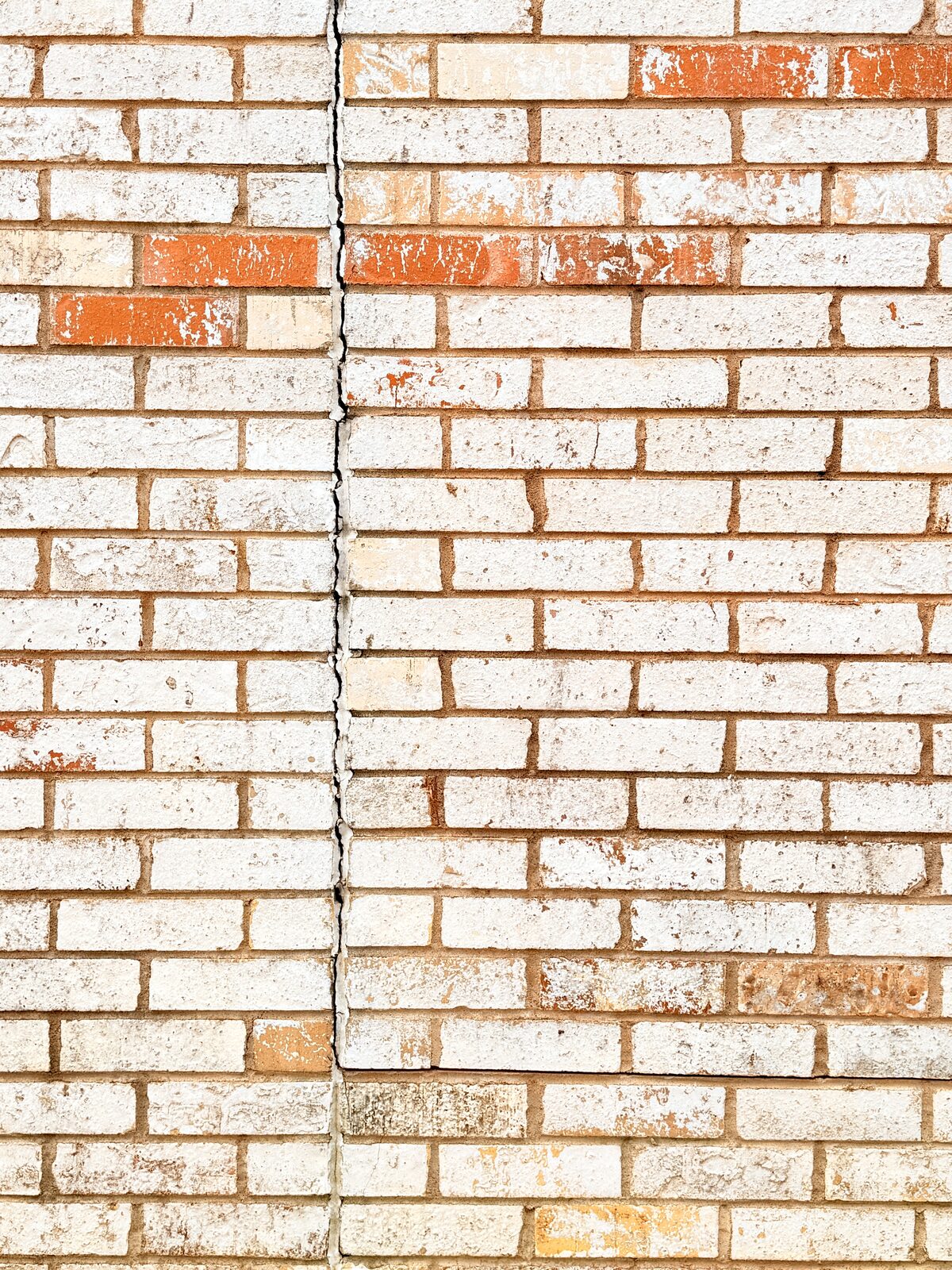Vertical crack-repair line through a brick wall section, tuckpointed after foundation stabilization