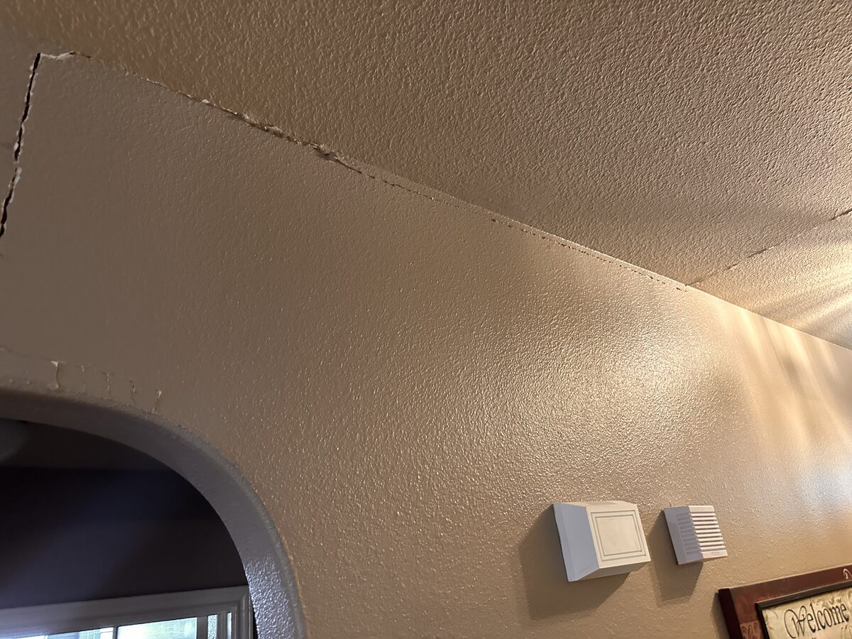 Separation crack along the wall-to-ceiling joint inside a home experiencing foundation movement