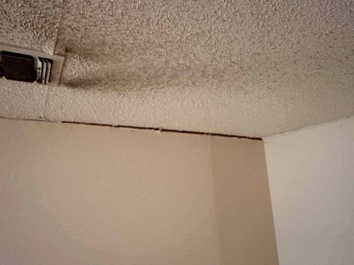 Separation gap opening where the wall meets a textured ceiling in a home with foundation movement