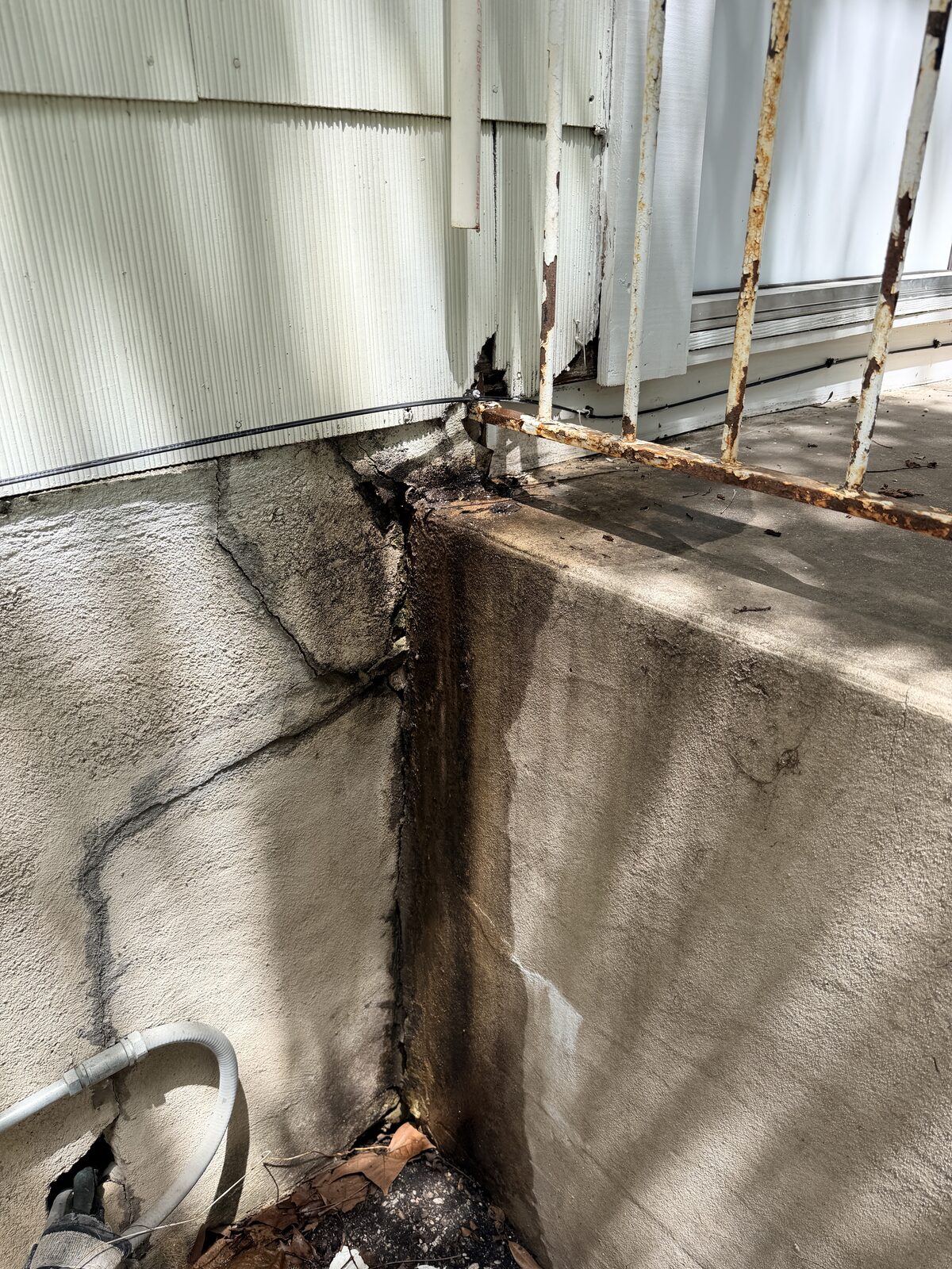 Deteriorated porch corner with moisture staining and a rusted railing