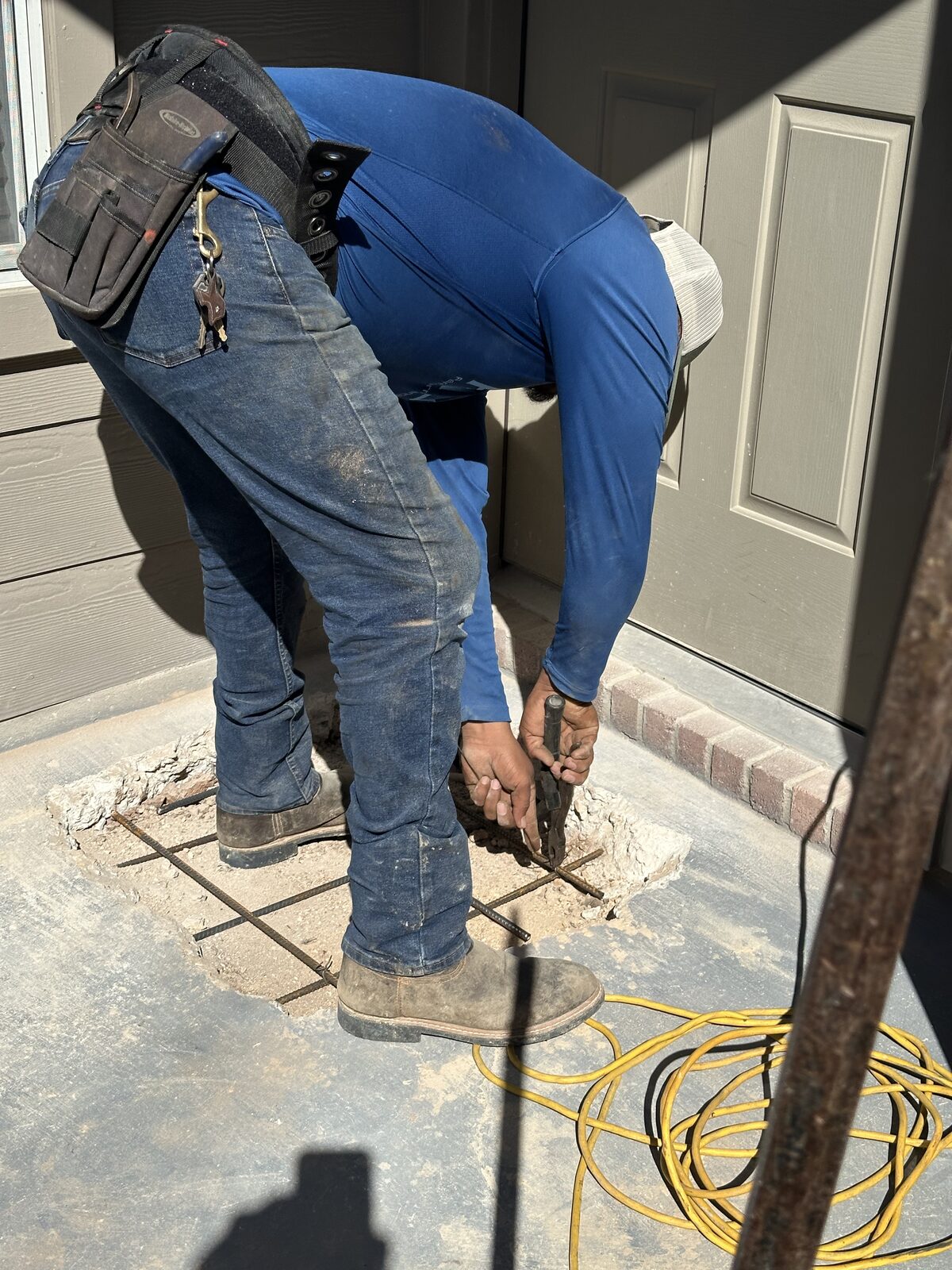 Technician tying rebar in a porch slab breakout before pouring back concrete during foundation repair