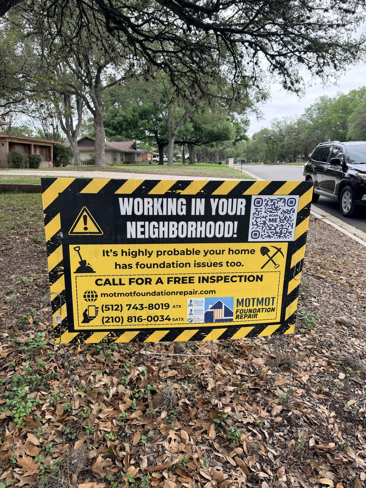 Foundation repair work underway behind a Motmot yard sign in a residential neighborhood