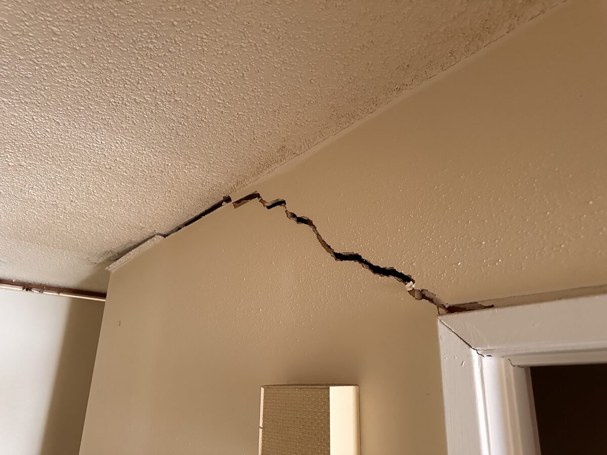 Zigzag crack at the peak of a vaulted ceiling wall, photographed during a foundation inspection