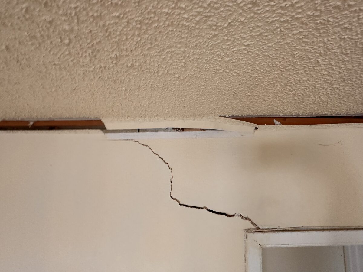 Zigzag crack and trim separation where the wall meets the ceiling in a settling home